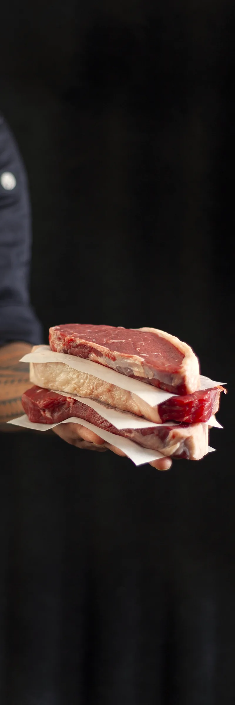 Steaks in butcher’s paper, held out across the counter