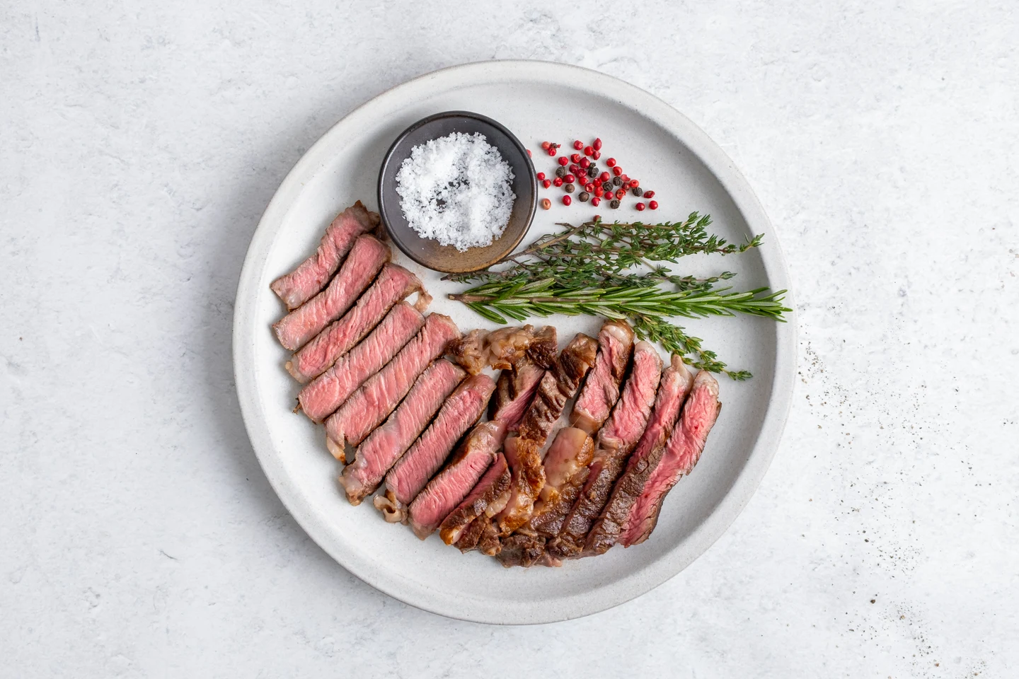 The cooked ribeye, sliced and served with herbs and salt