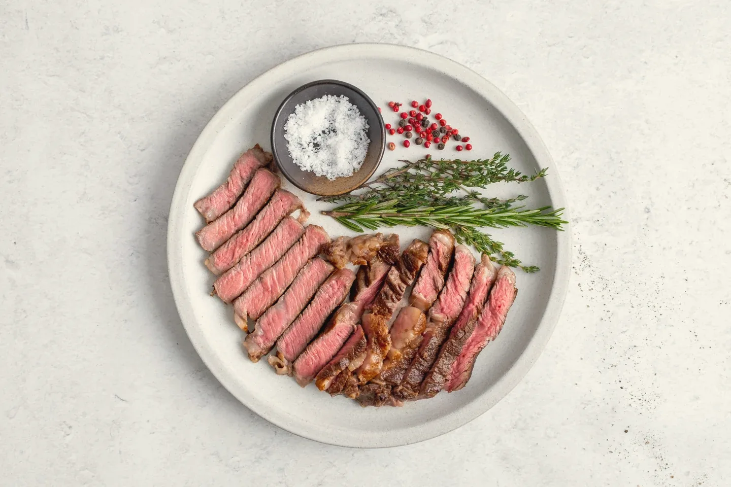 The cooked ribeye, sliced and served with herbs and salt